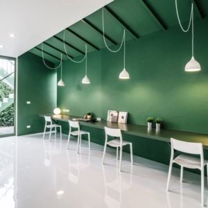 Work space with green wall and white chairs agains the wall